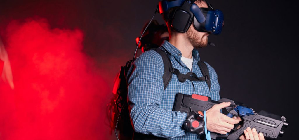 Trainee using virtual reality headset, weapon, and motion sensor in a smoke-filled space