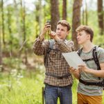 Two students searching for a geocache. Photo credit: Adobe Stock